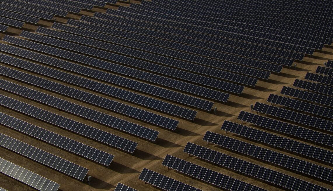 Large scale solar farm integrated with massive battery storage containers in a desert landscape