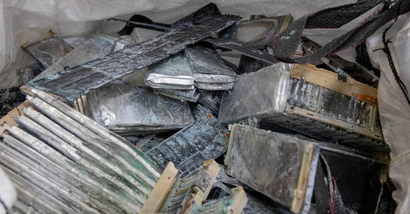 A pile of discarded lithium-ion battery cells waiting for processing in a warehouse