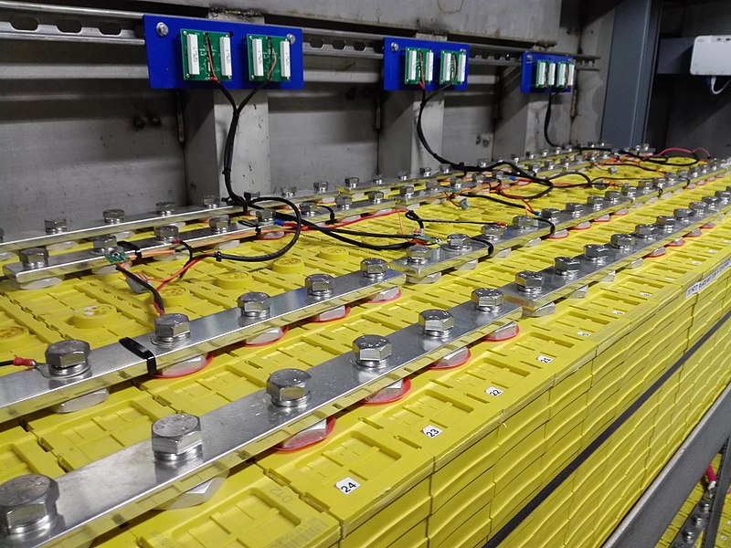 A modern solar inverter and battery storage system mounted on a garage wall in a European suburb