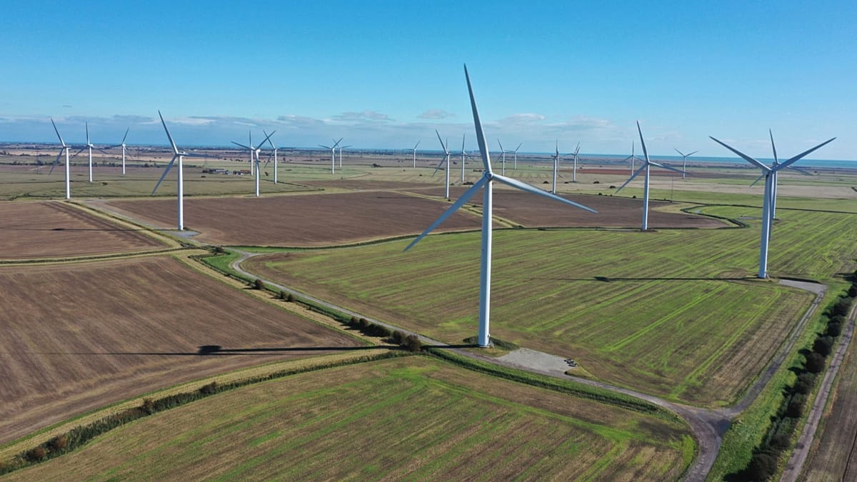 A modern wind farm under a cloudy European sky with a digital grid overlay icon