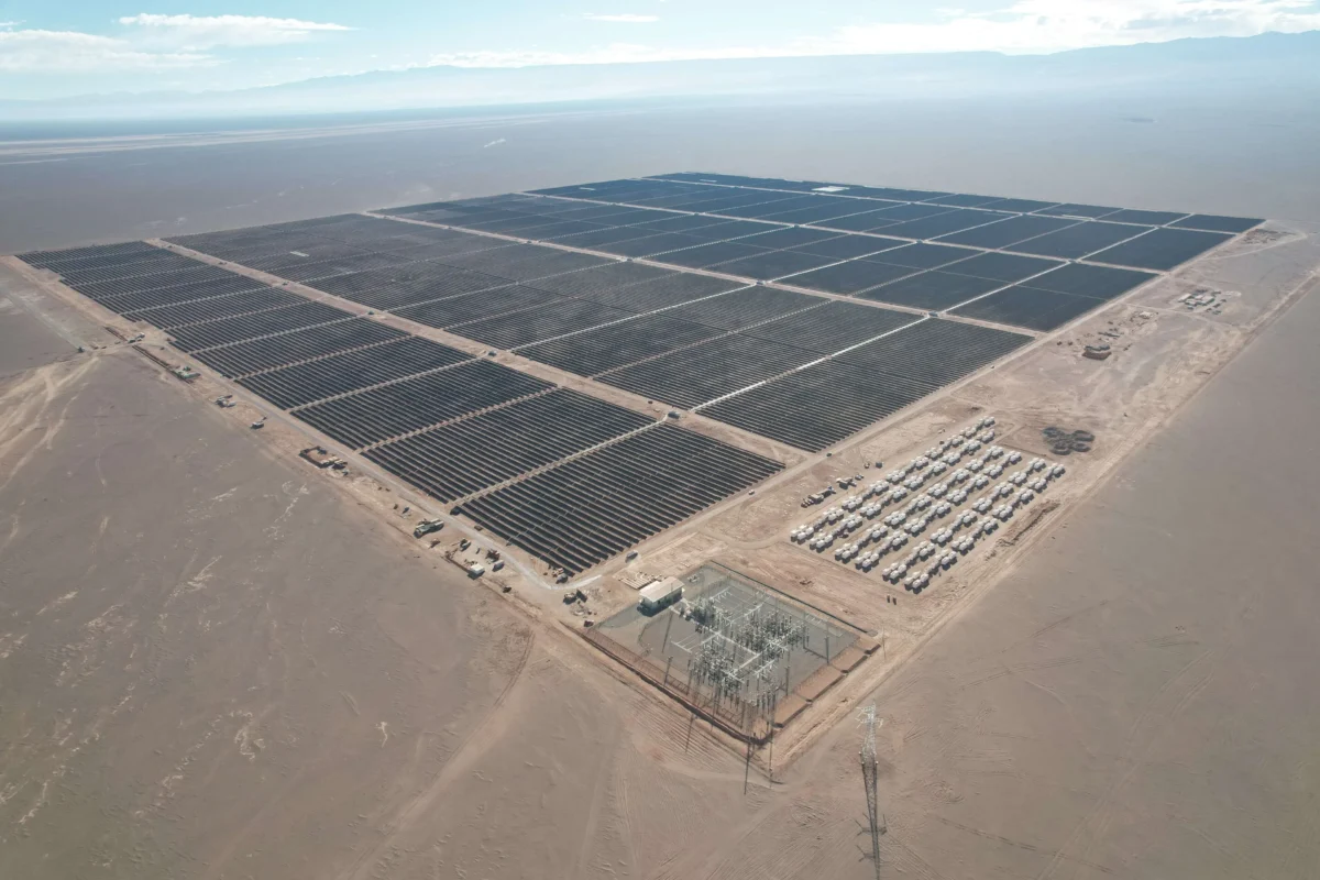 Aerial view of a massive utility-scale solar farm with integrated battery storage containers