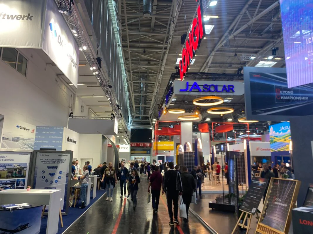 Crowded exhibition floor at a major solar energy trade show with large blue module displays.