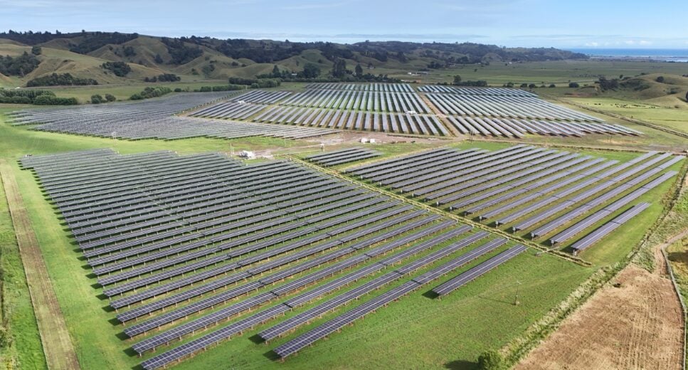 Aerial view of a large-scale solar farm construction site with workers installing PV mounting structures.