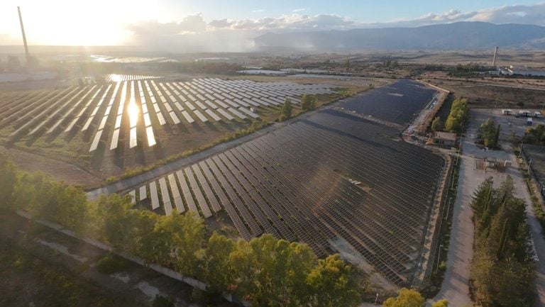 Aerial view of a large-scale solar panel installation under construction in the Italian countryside.