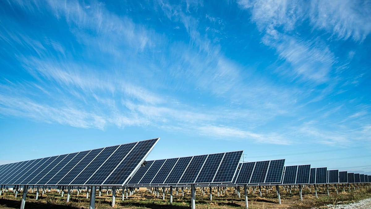 Large scale solar farm construction site under cloudy European sky with heavy machinery visible