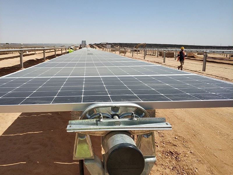 Aerial view of a large-scale solar farm layout with rows of photovoltaic panels in a rural landscape.