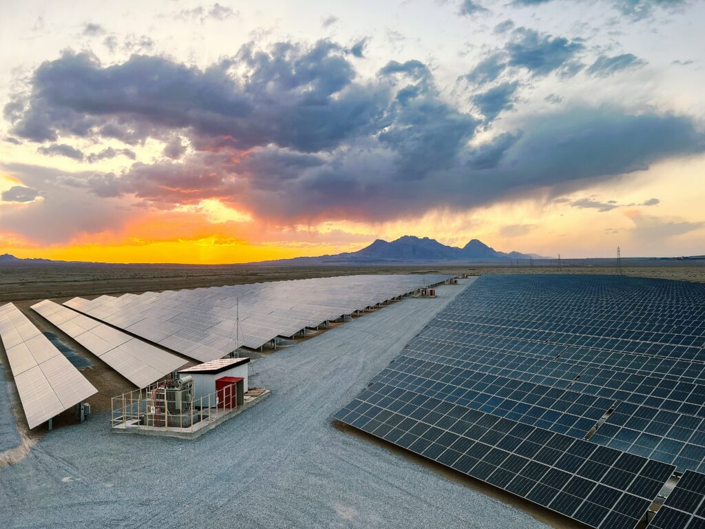 Aerial view of a large-scale solar farm under construction near industrial facilities.