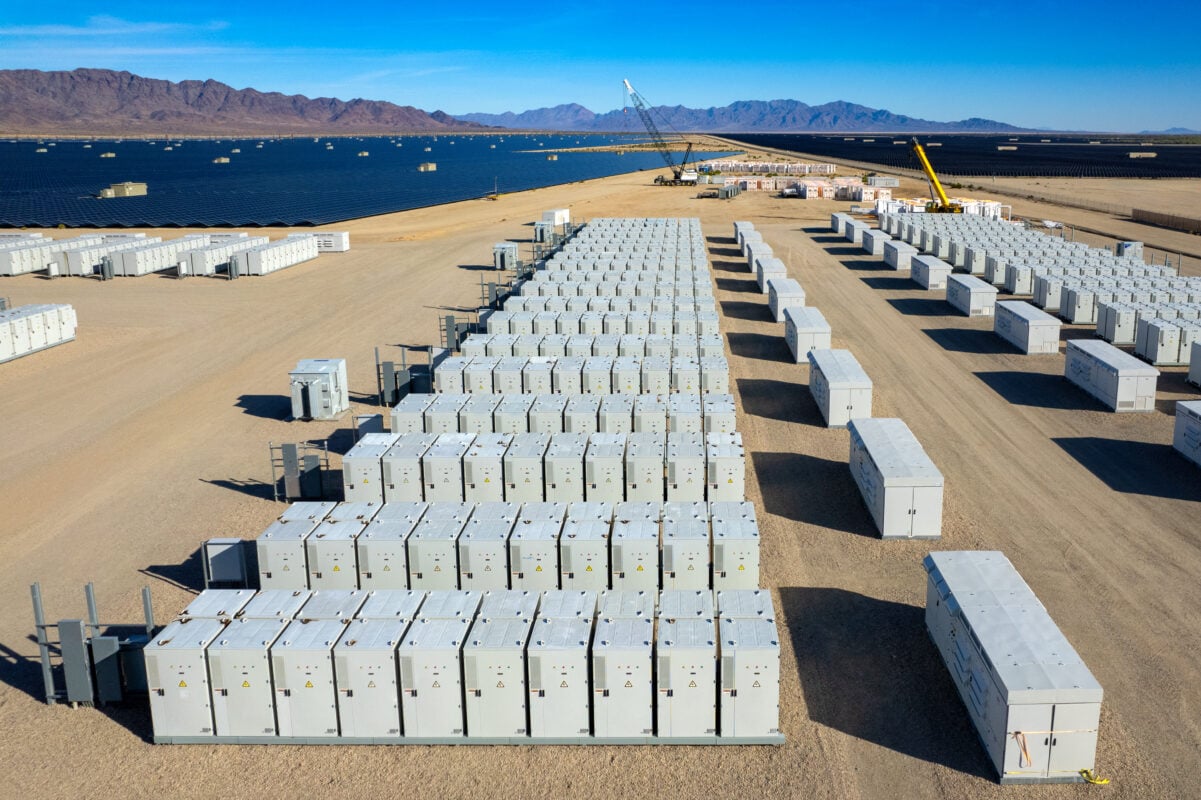 Technician inspecting a battery energy storage system (BESS) container in a solar field.