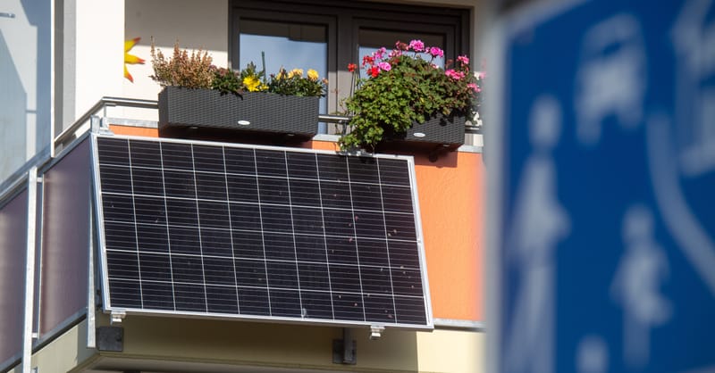 Modern apartment balcony featuring a compact, sleek solar panel mounted to the railing.