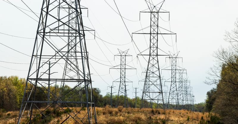 A technician installing a smart energy meter next to a residential solar inverter setup.