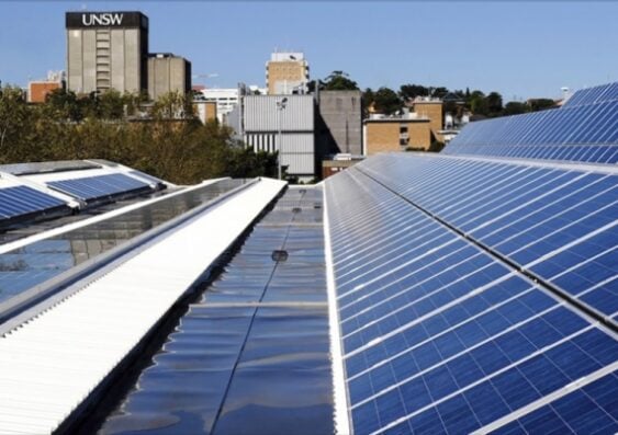 A close-up view of solar panels under sunlight with a researcher examining UV degradation effects on photovoltaic materials.