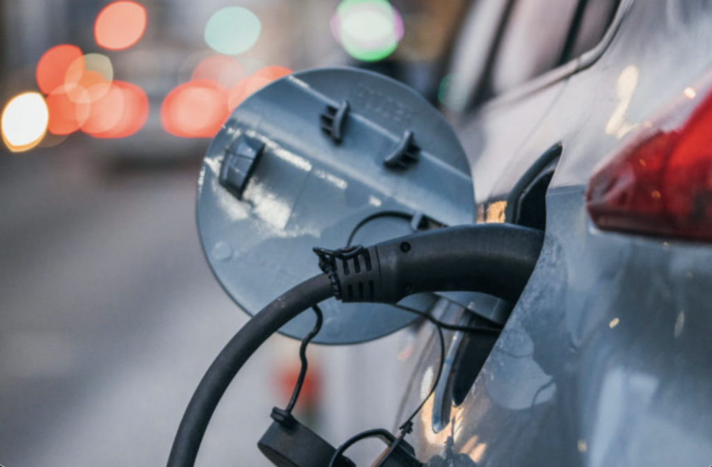 Electric vehicles plugged into charging stations at a grid flexibility demonstration site in Germany.