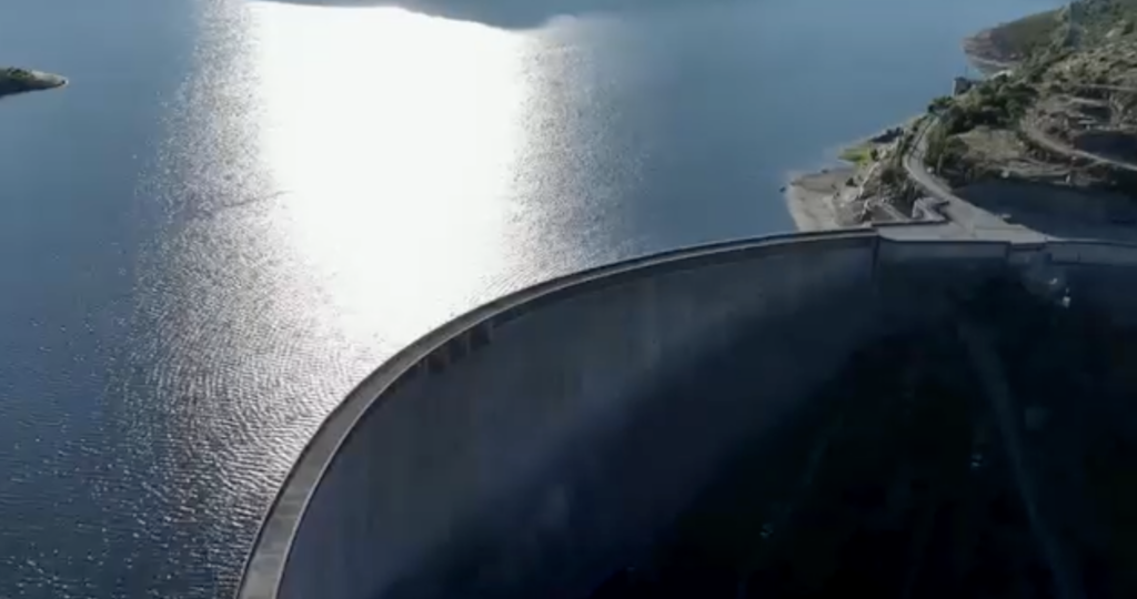 Aerial view of a pumped hydro storage facility with solar panels in the background