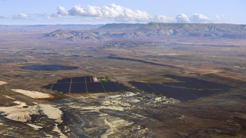 A vast solar panel field under a bright, clear blue sky.