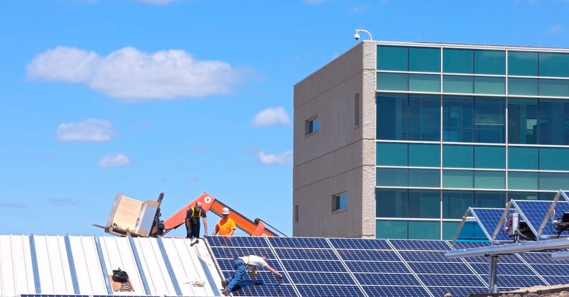 A technician inspecting a residential battery storage system connected to a solar array.