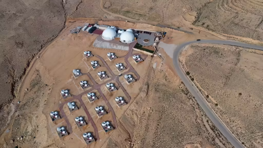 Aerial view of a solar photovoltaic installation layout near industrial infrastructure facilities.