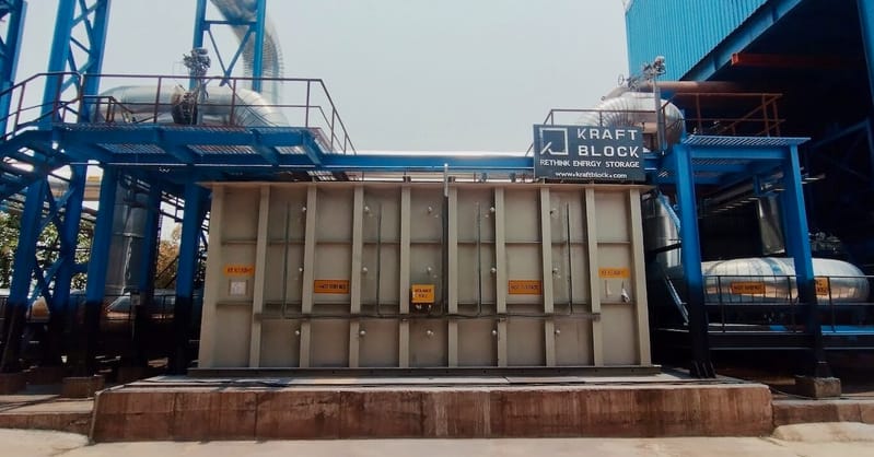 A modular Kraftblock thermal storage unit installed next to heavy industrial steel manufacturing infrastructure.