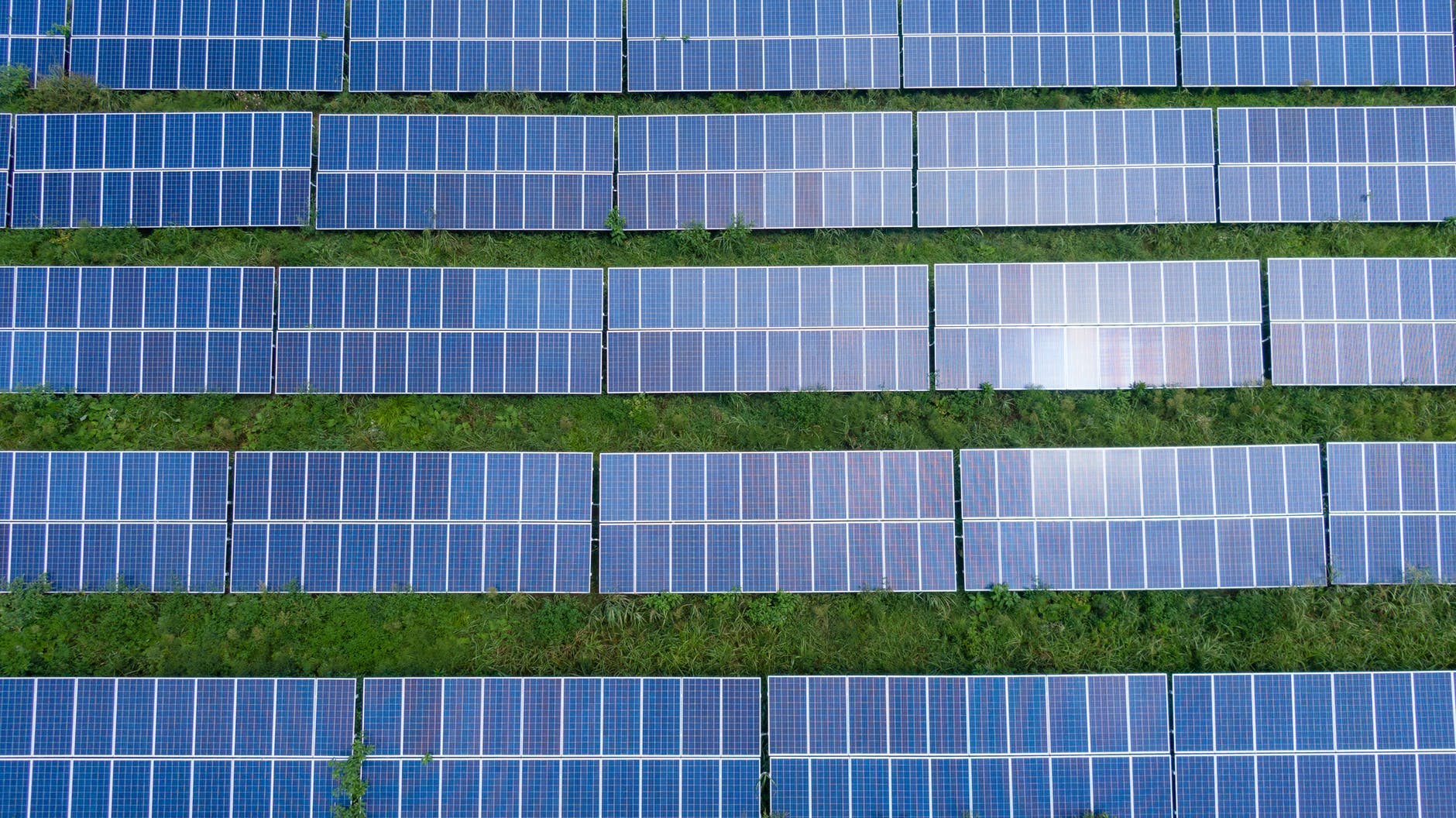 Aerial view of a massive utility-scale solar power plant with thousands of blue photovoltaic panels