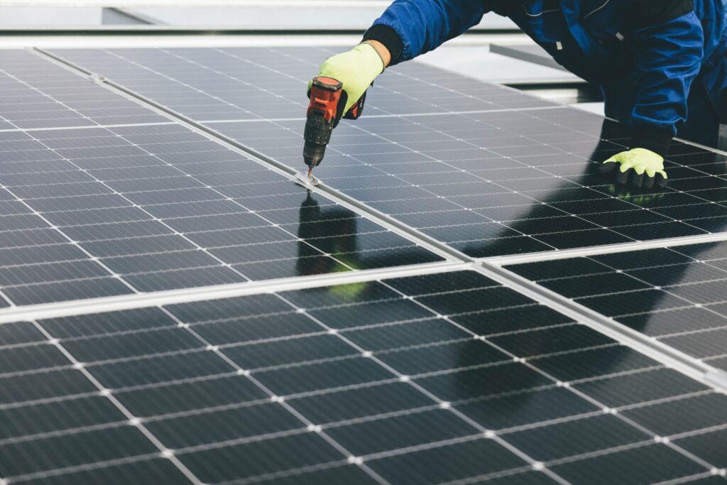 Solar technician performing maintenance on utility-scale photovoltaic panels in a field