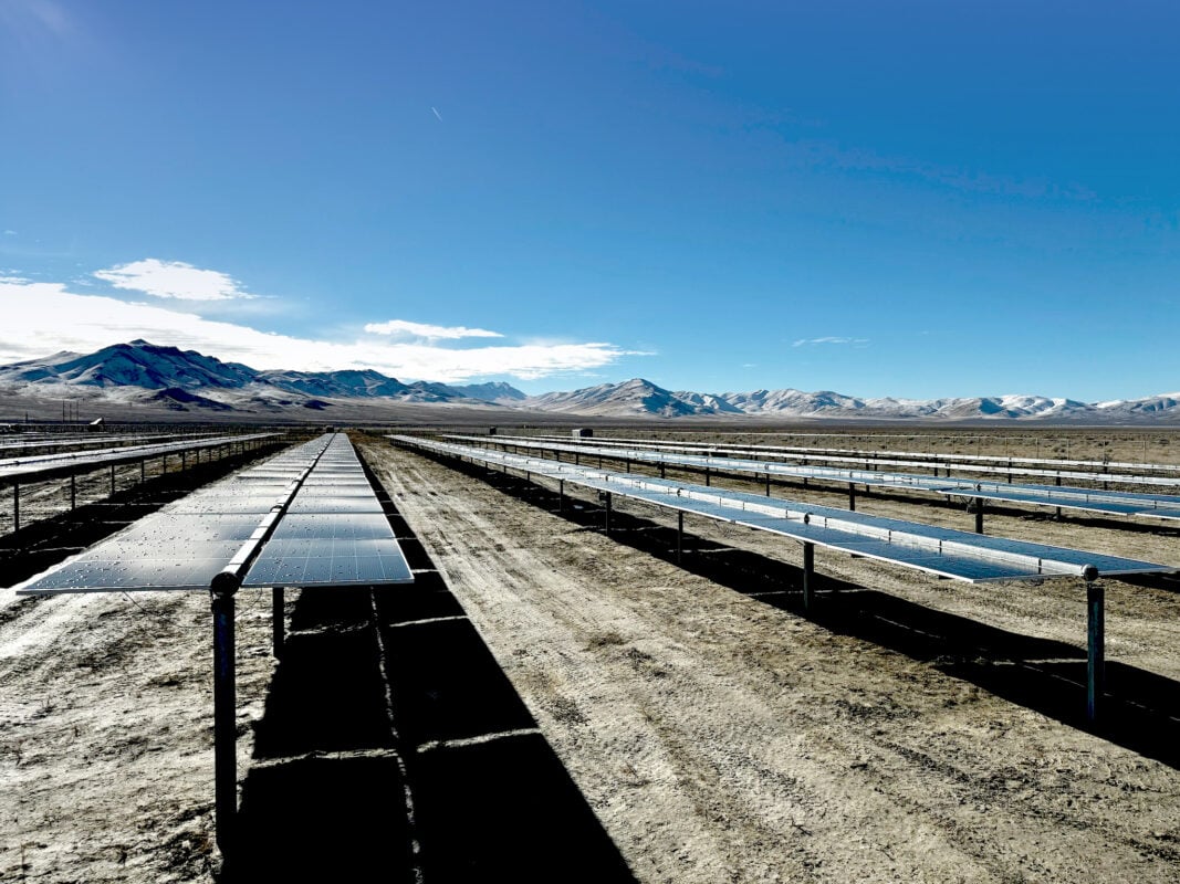 Large scale solar farm under construction with stacks of shipping containers in the background