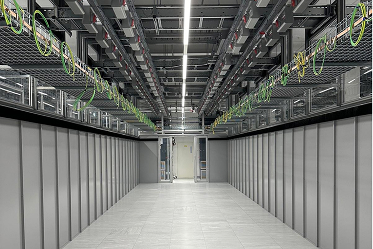 A modern data center facility with solar panels installed on its roof and surrounding land.