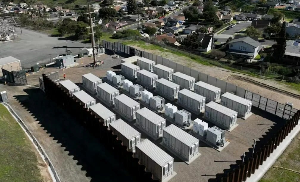 Rows of utility-scale battery storage containers integrated with a large-scale solar PV array.