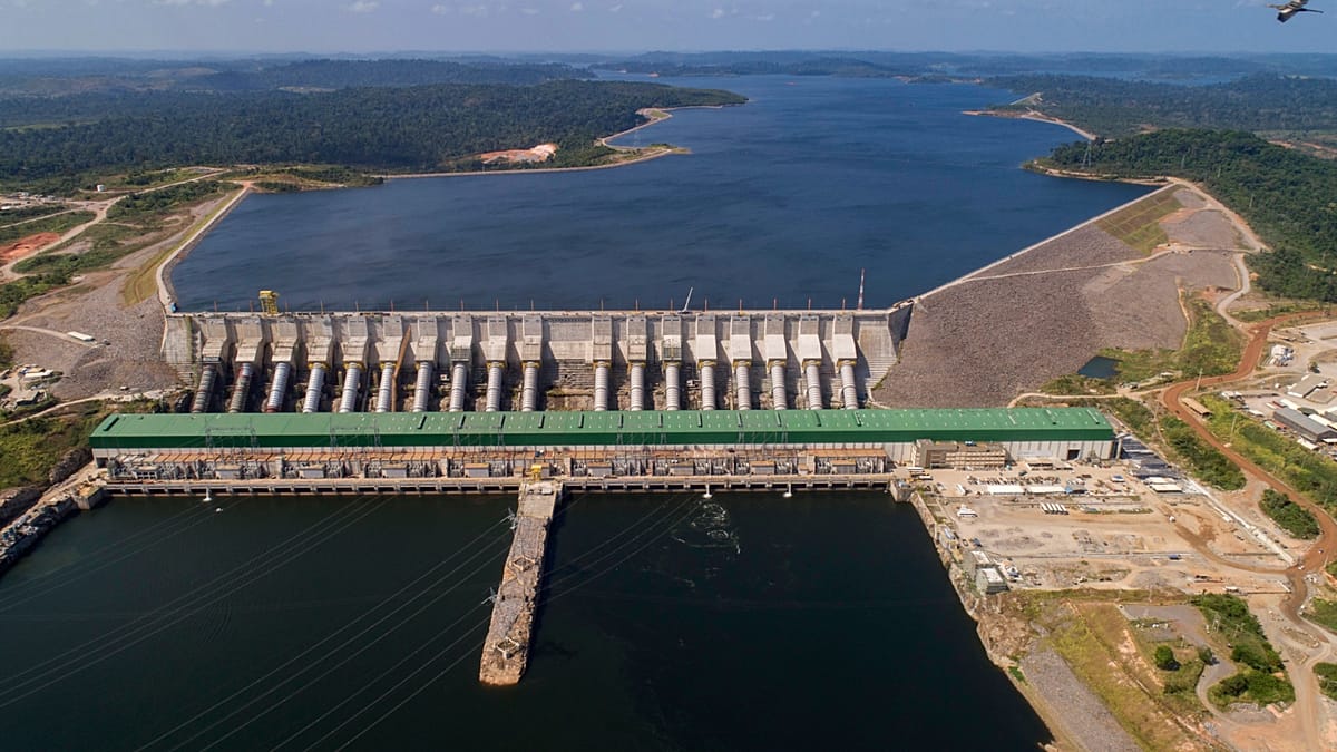 A massive hydroelectric dam structure with water flowing, symbolizing the risks of large-scale energy projects.