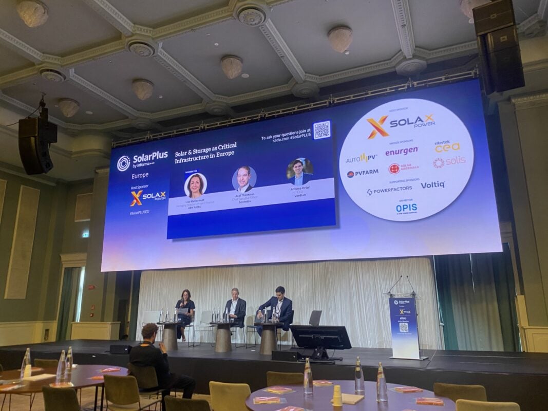 A grid-scale BESS container next to a commercial solar rooftop installation in Italy