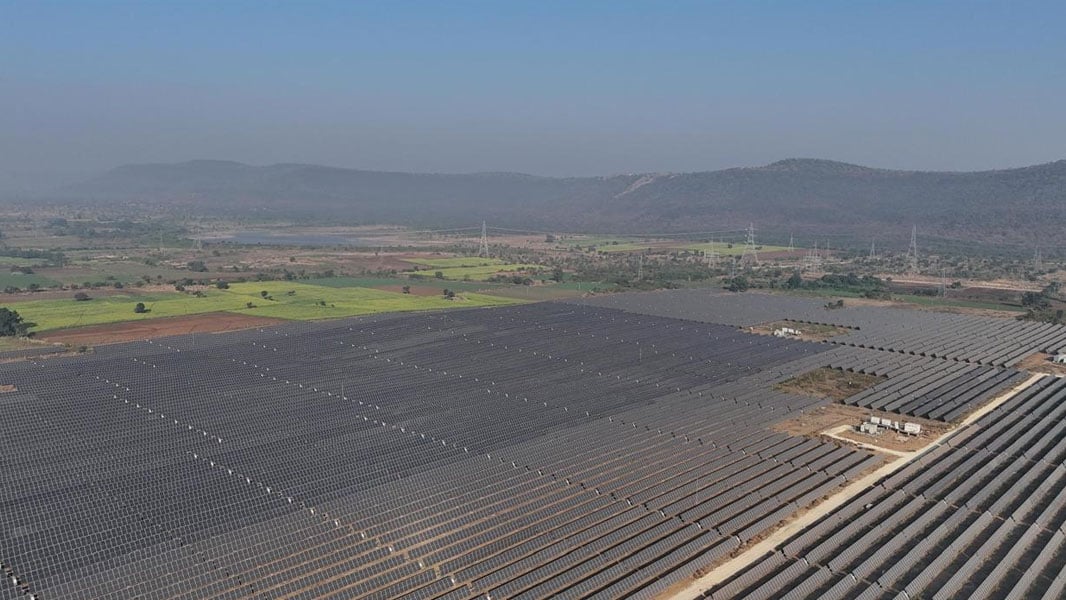 Aerial view of a massive utility-scale solar farm in India with rows of PV panels.