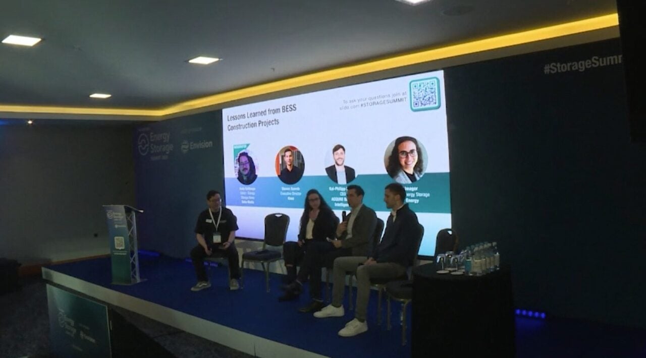 Engineer inspecting complex battery energy storage system cabling and data connections on a construction site.