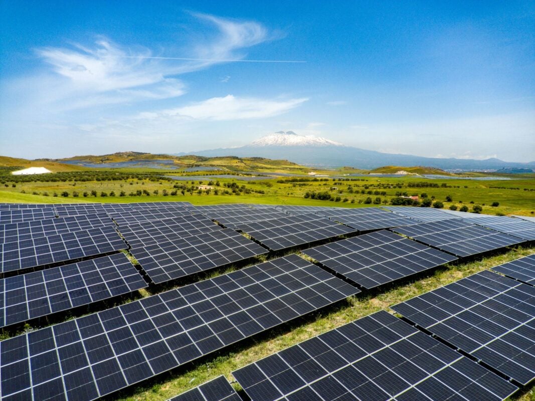 Aerial view of a massive solar farm with thousands of panels stretching across Italian hillsides.
