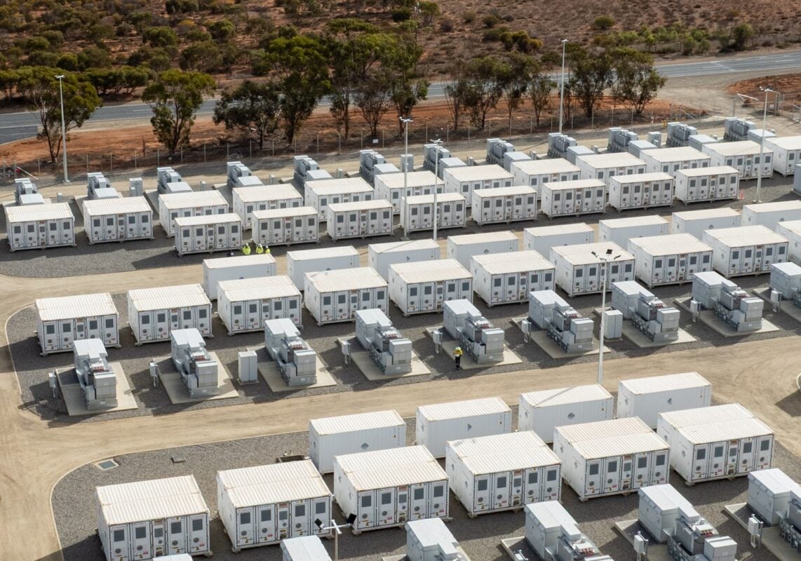 Large scale battery energy storage system containers in a grid-connected field during sunset.