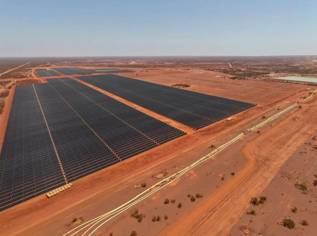 Aerial view of a massive utility-scale solar farm in the Australian outback with battery storage units.