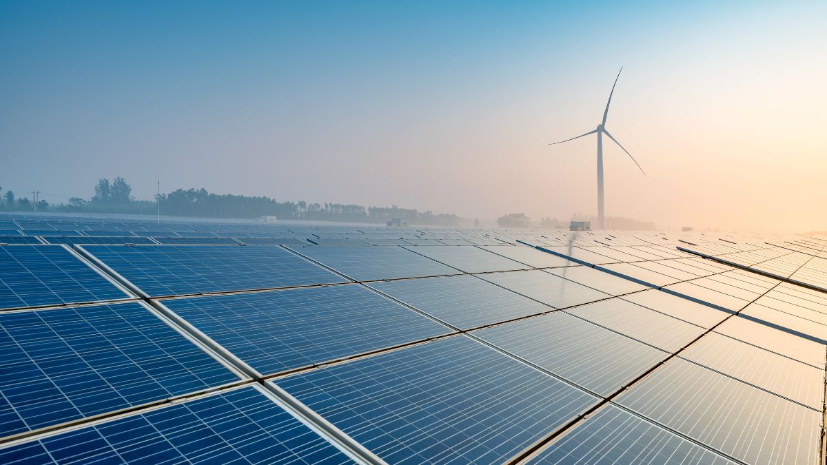 A large scale solar farm under construction with workers installing photovoltaic panels in a dusty environment.