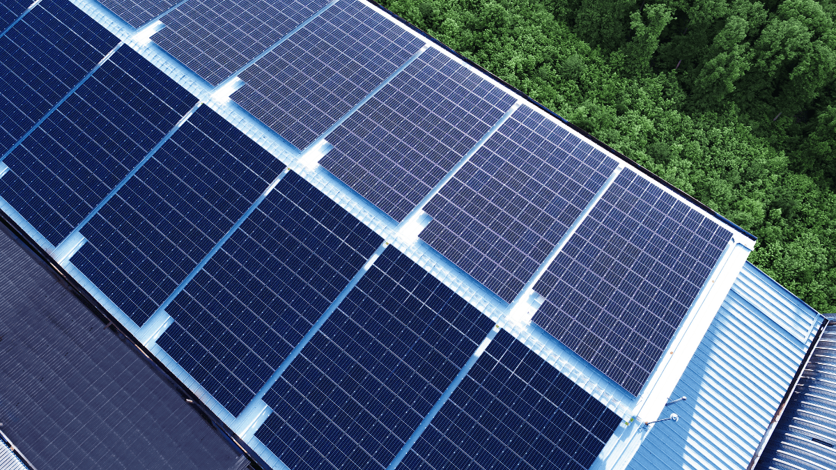 Modern solar panels installed on a commercial rooftop with air conditioning units nearby.