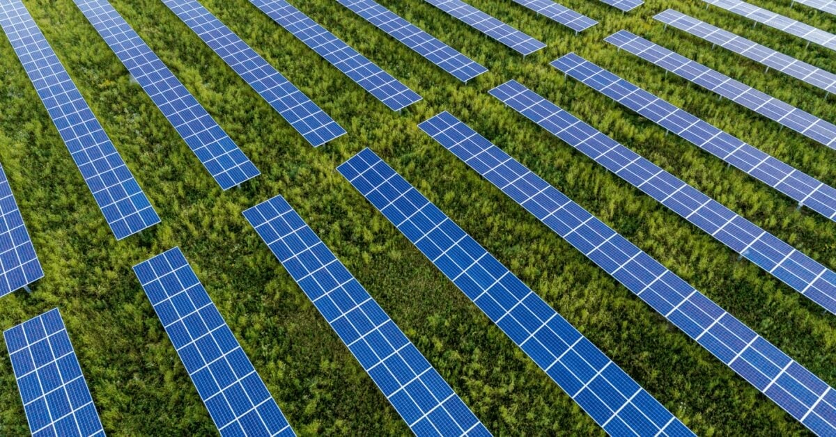 Aerial view of a massive utility-scale solar farm with thousands of blue panels in a grid.