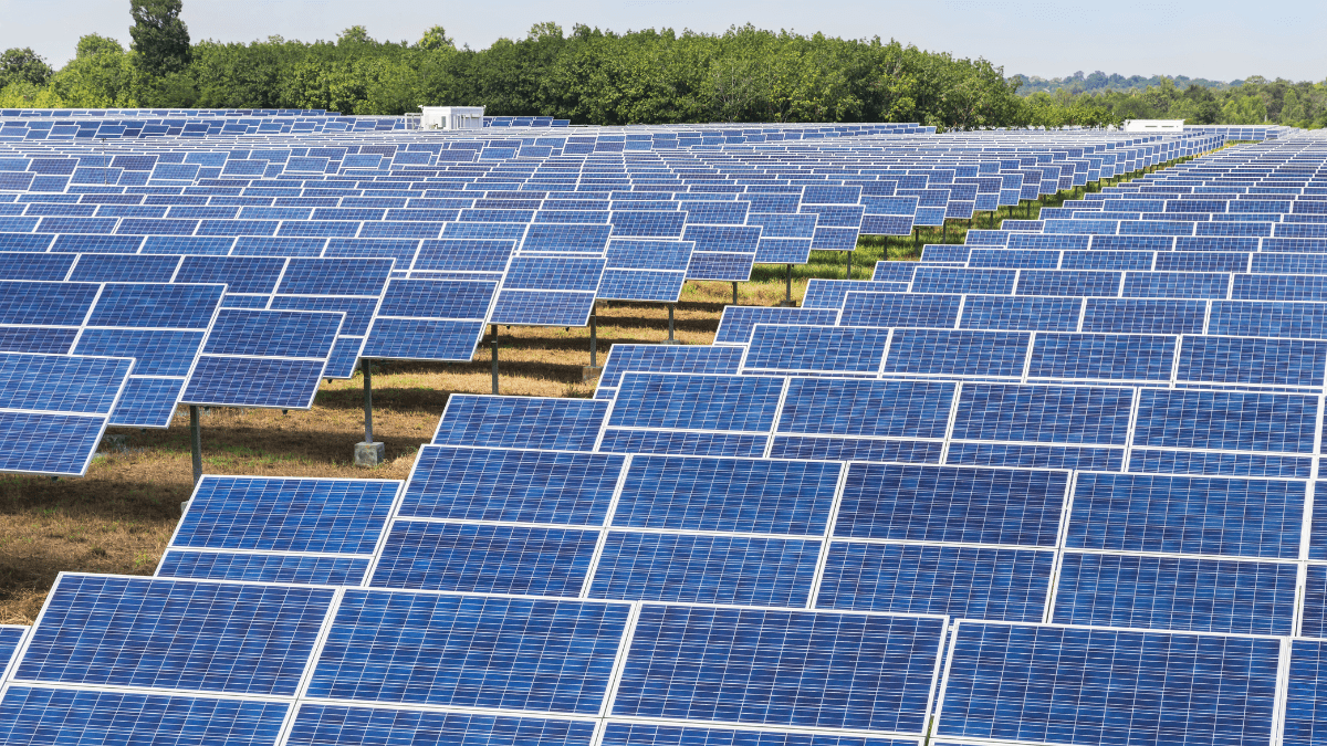 Large industrial power transformer in a high-voltage substation with solar panels in the background