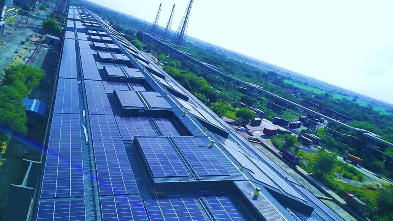 Large scale solar farm with battery storage containers under a bright blue sky
