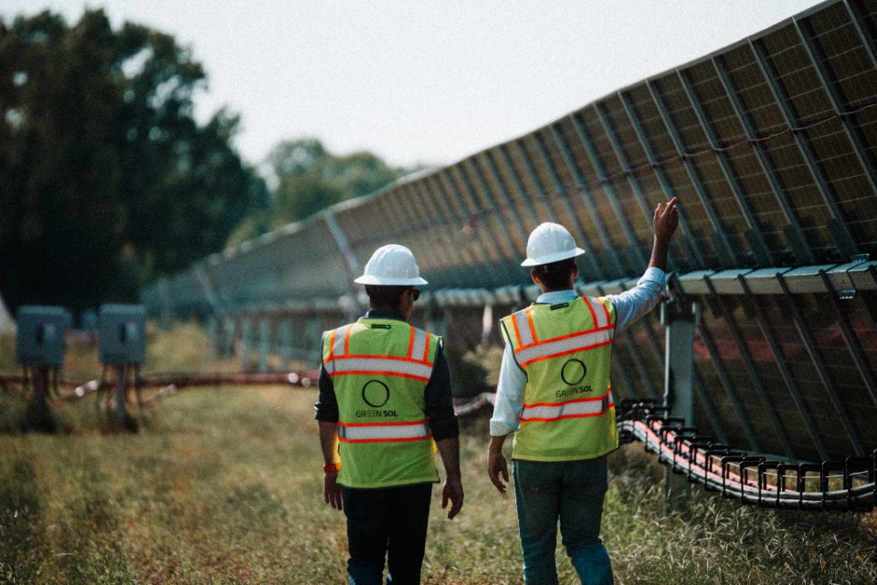 Aerial view of a large-scale utility solar farm with rows of photovoltaic panels.