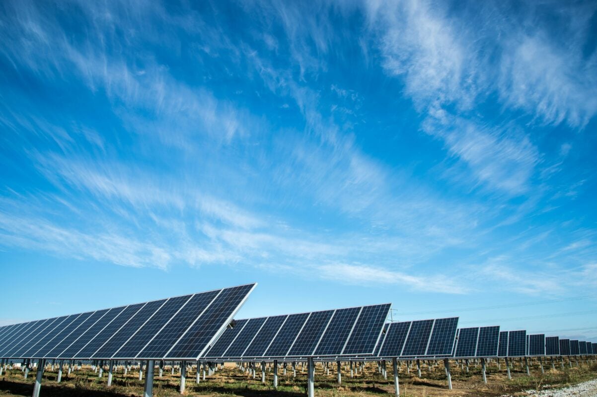 A professional rebranding logo transition from REC Solar to REC Power against a backdrop of a commercial solar and battery storage site.
