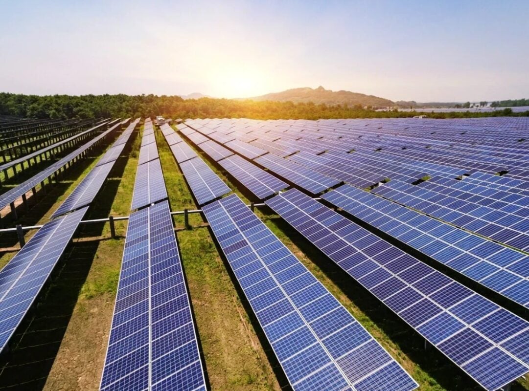 Large scale solar farm construction site with rows of battery energy storage containers being installed