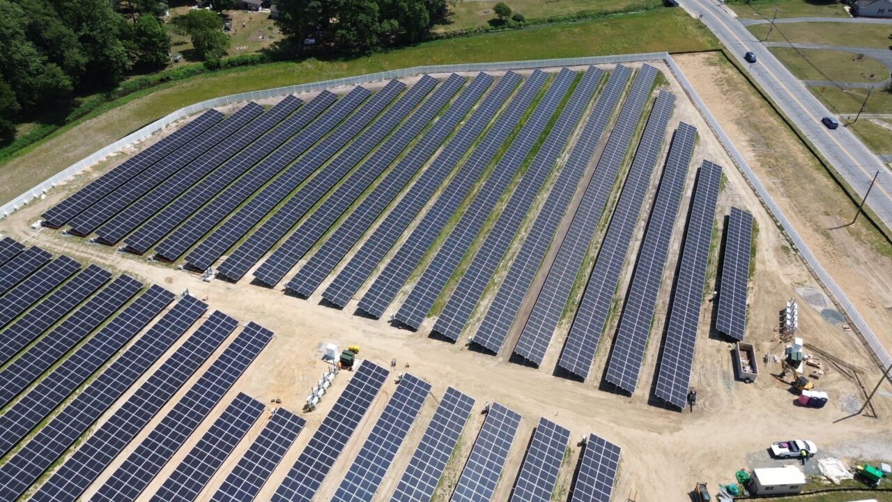 Aerial view of a commercial rooftop solar installation with high-density PV modules and modern inverters.