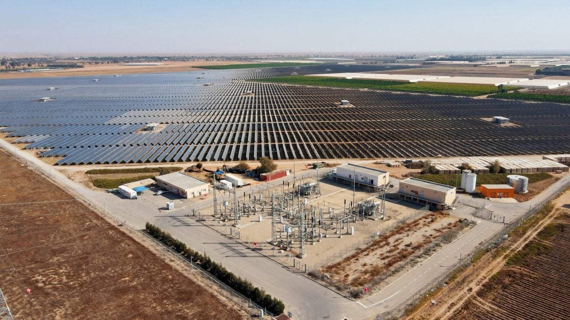 Aerial view of a large-scale solar farm with industrial-sized battery storage units nearby