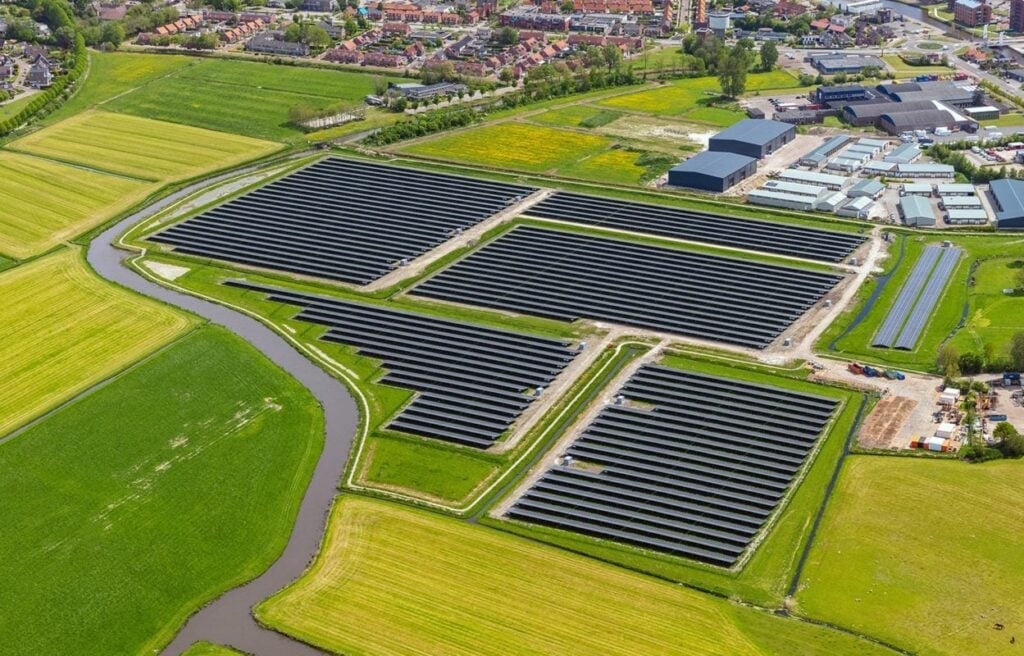 A technician reviewing a financial spreadsheet next to a commercial solar array.