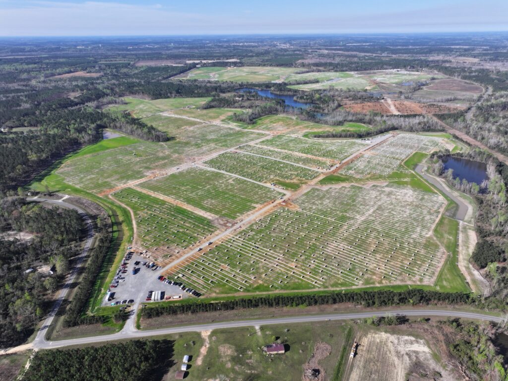 Aerial view of a large-scale solar farm in Spain with integrated containerized battery storage systems.
