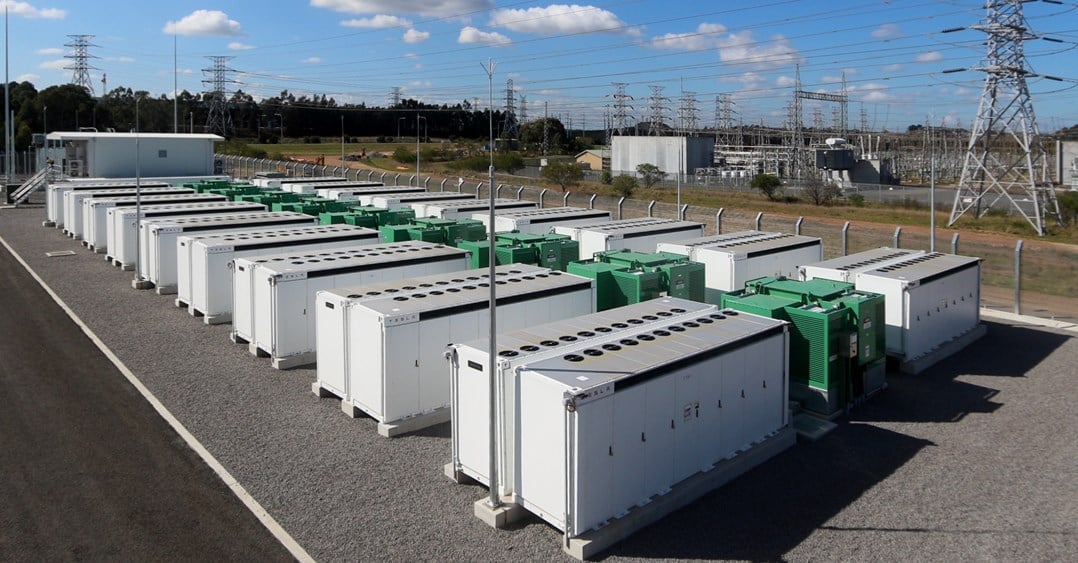 Large scale lithium-ion battery energy storage system facility under a bright blue sky.
