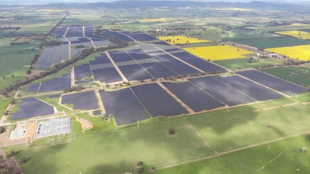 A modern data center facility with an adjacent large-scale solar farm and battery storage containers.