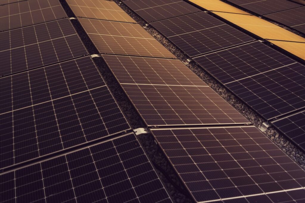 Aerial view of a commercial solar array on a white Spanish rooftop under a clear blue sky.