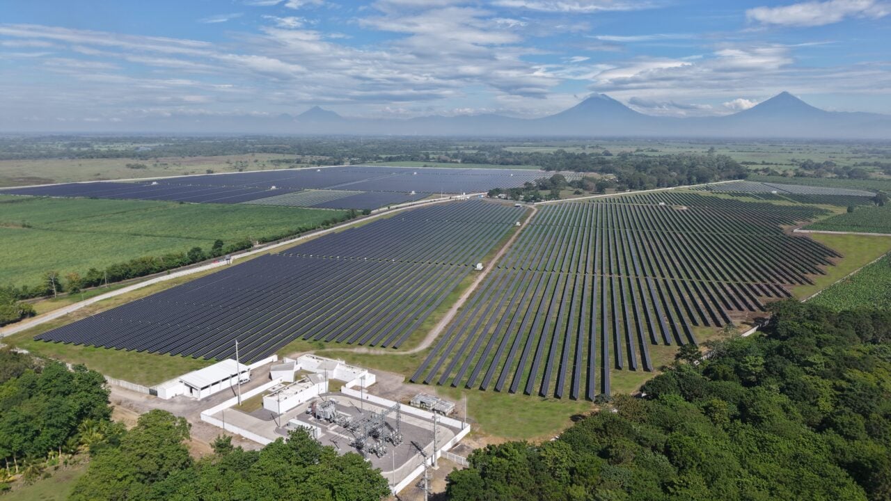 Aerial view of a large-scale solar farm under a clear sky, representing international project development.