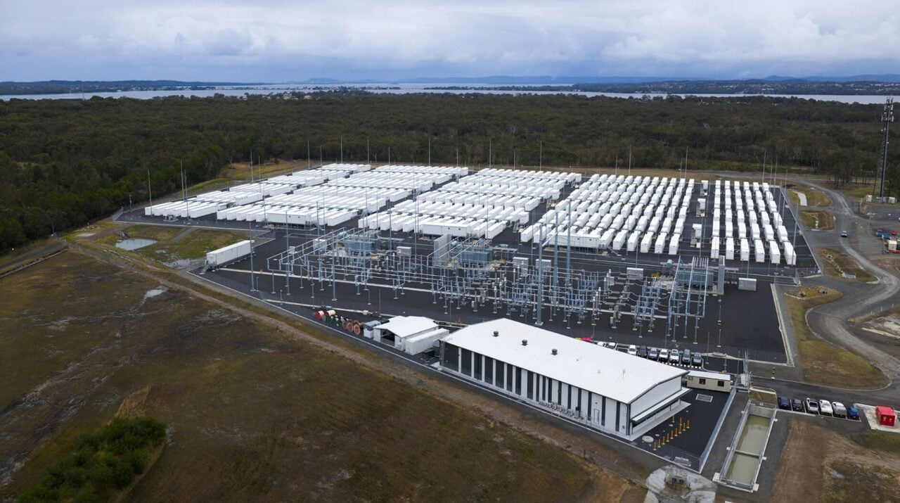 A modern residential home with rooftop solar panels and a battery storage system unit.